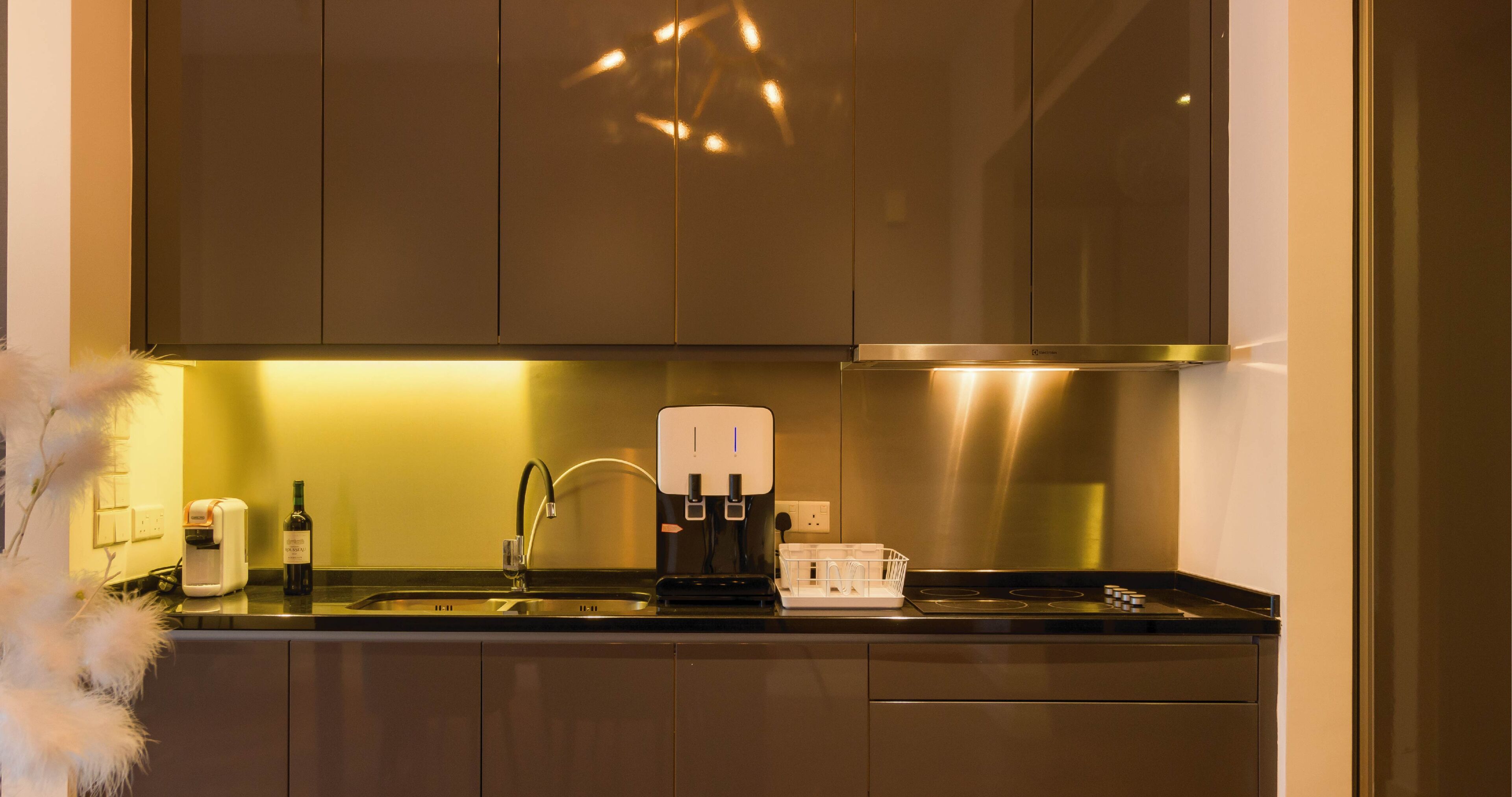 A modern kitchen with stainless steel appliances, a coffee maker, and a wine bottle.
