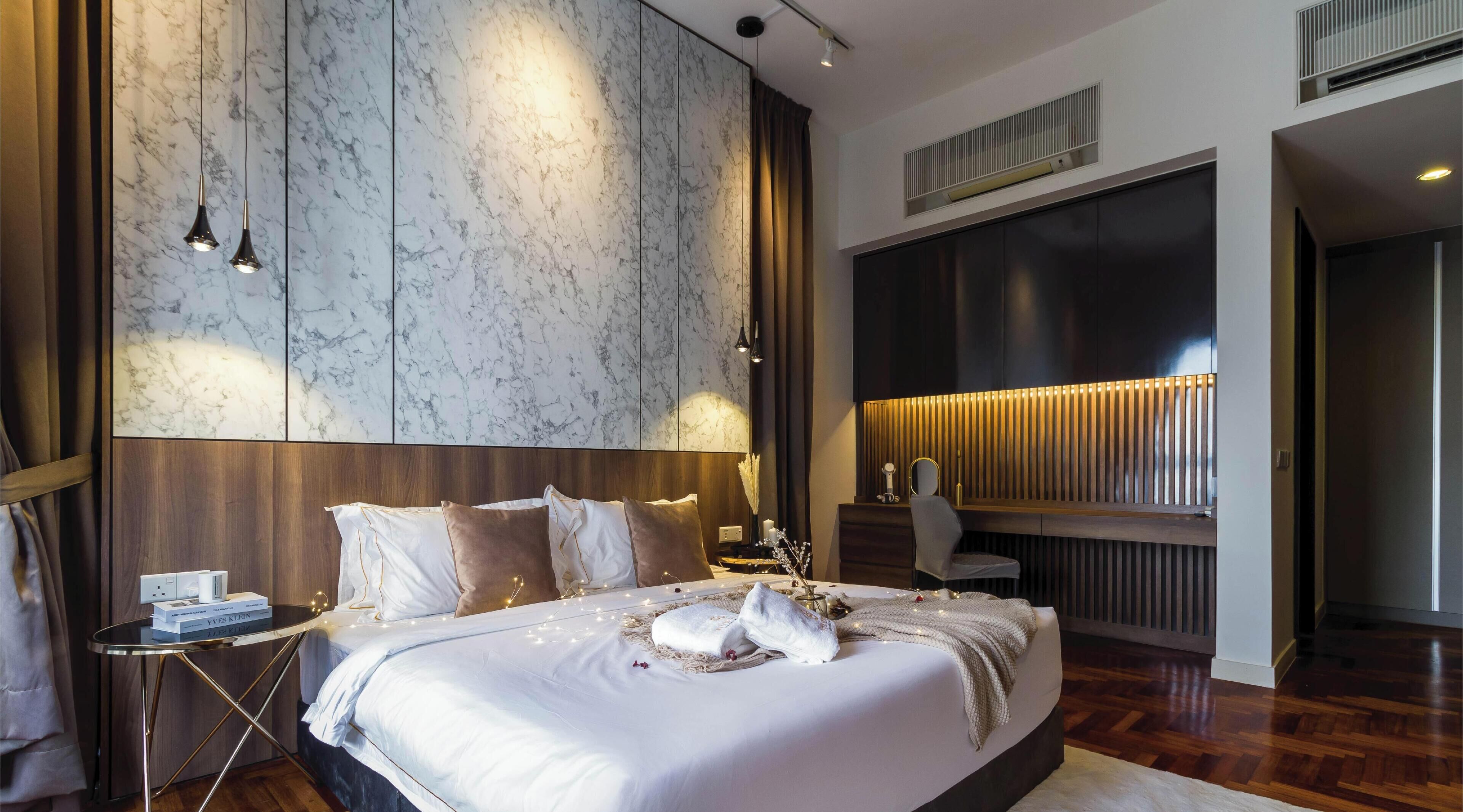A modern bedroom with a large bed, a bedside table, a nightstand, a mirror, and a wall-mounted light.