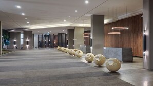 A modern lobby with a long reception desk, multiple columns, and spherical decorative elements. - The Mews KLCC by Five Senses (Kuala Lumpur)