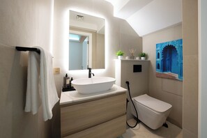 A modern bathroom with a white sink, a mirror, a toilet, and a shower. - Luxury Short Term Stay 2BHK plus Maids - RANCHES (Dubai)