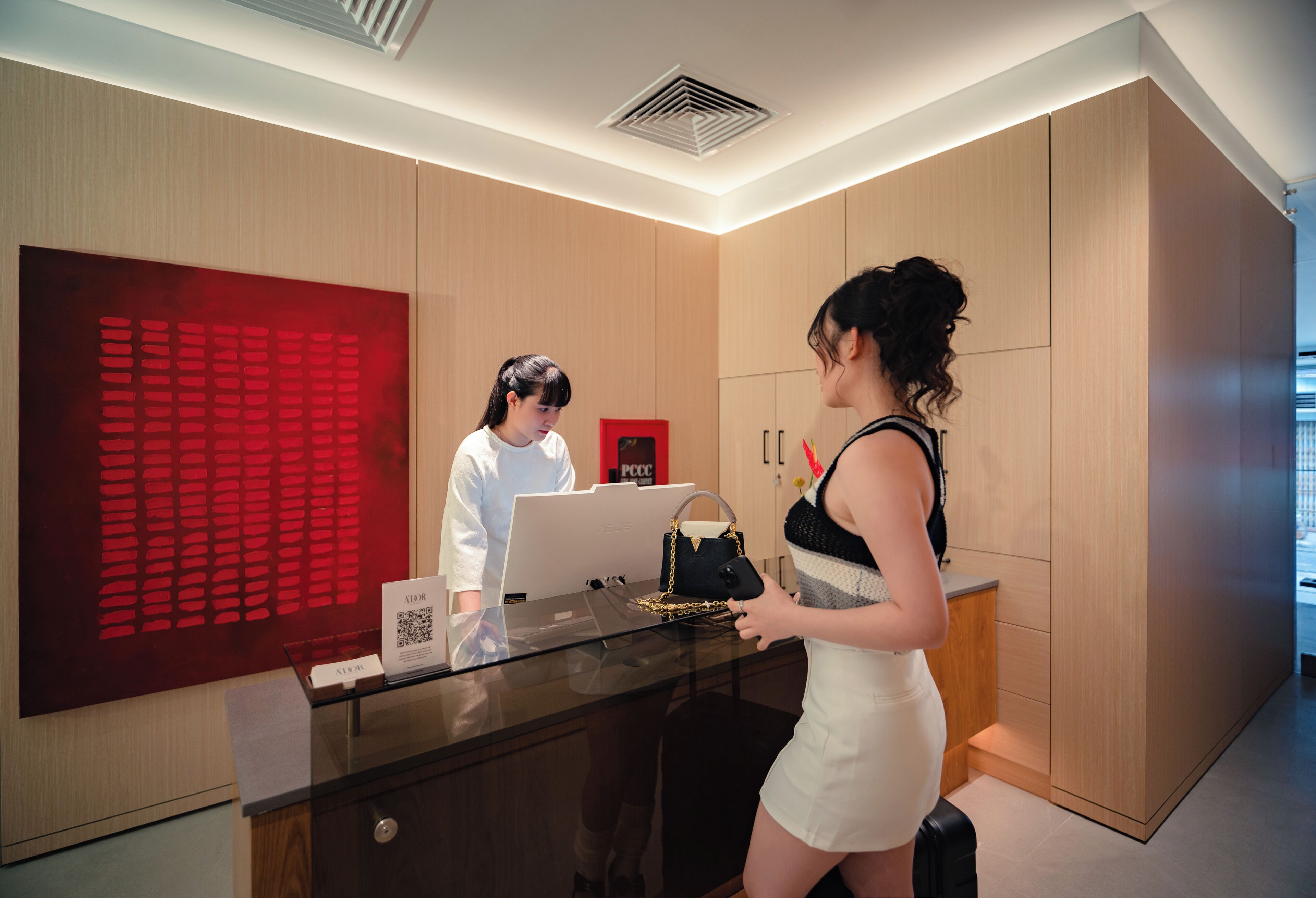 A reception desk with a glass top, a red decorative panel, and a sign with QR code.