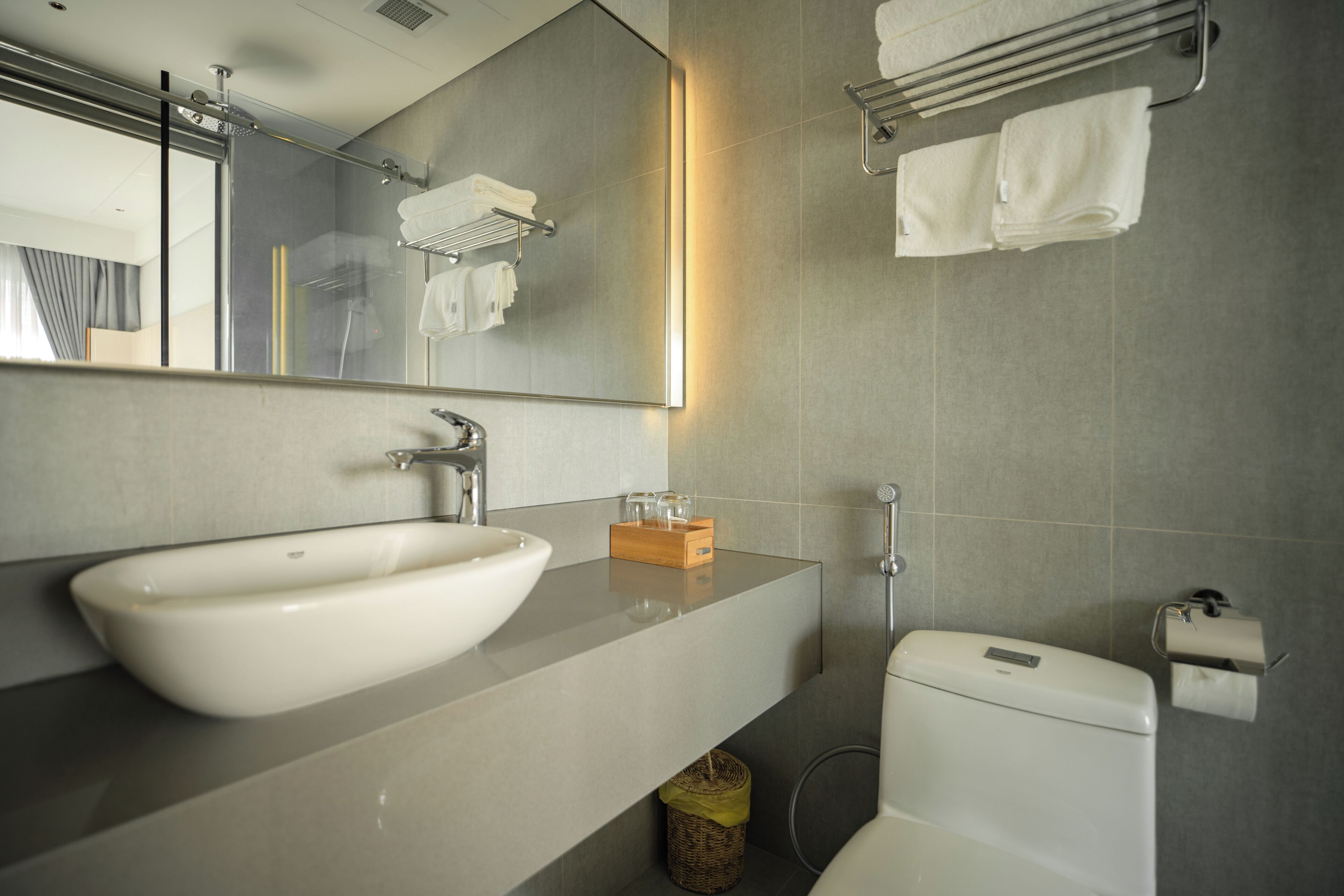 Un baño moderno con un lavamanos grande, espejo, toallero y retrete.