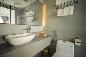 Un baño moderno con un lavamanos grande, espejo, toallero y retrete.