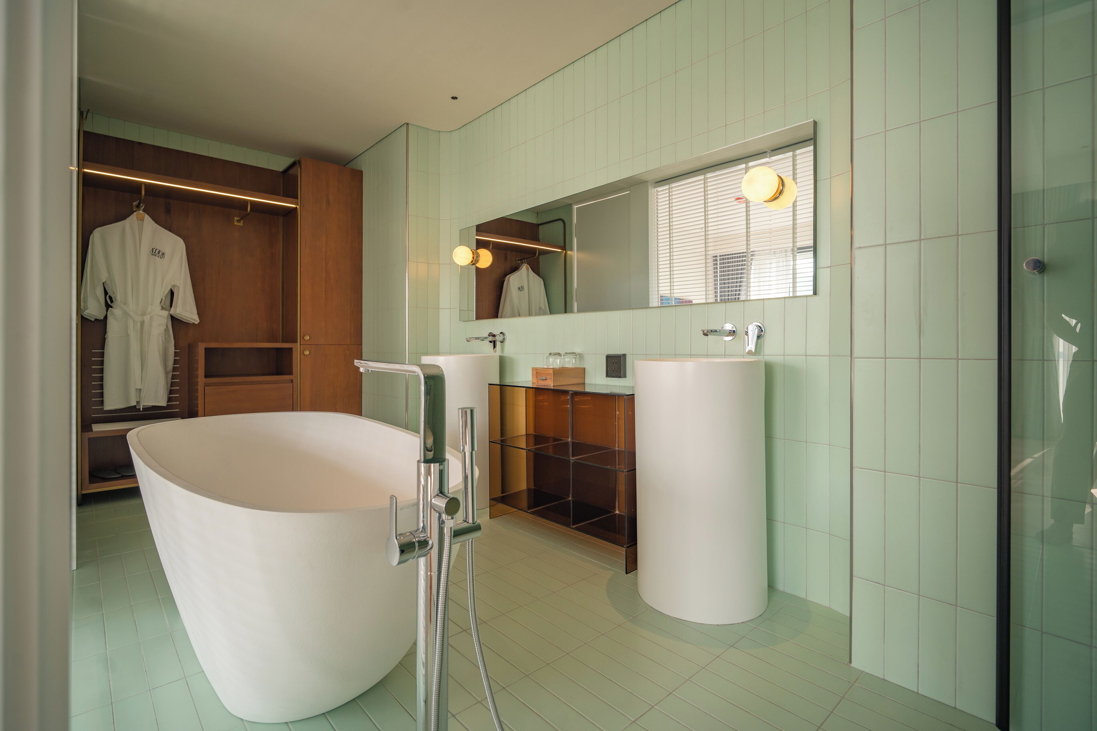 A modern bathroom with a freestanding bathtub, a vanity with a mirror, and a walk-in closet with wooden doors.