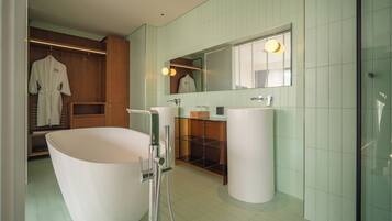 Un baño moderno con una bañera independiente, un tocador con espejo y un vestidor con puertas de madera.