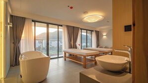 Une salle de bain moderne avec une baignoire sur pieds, un grand lavabo et une table de massage.