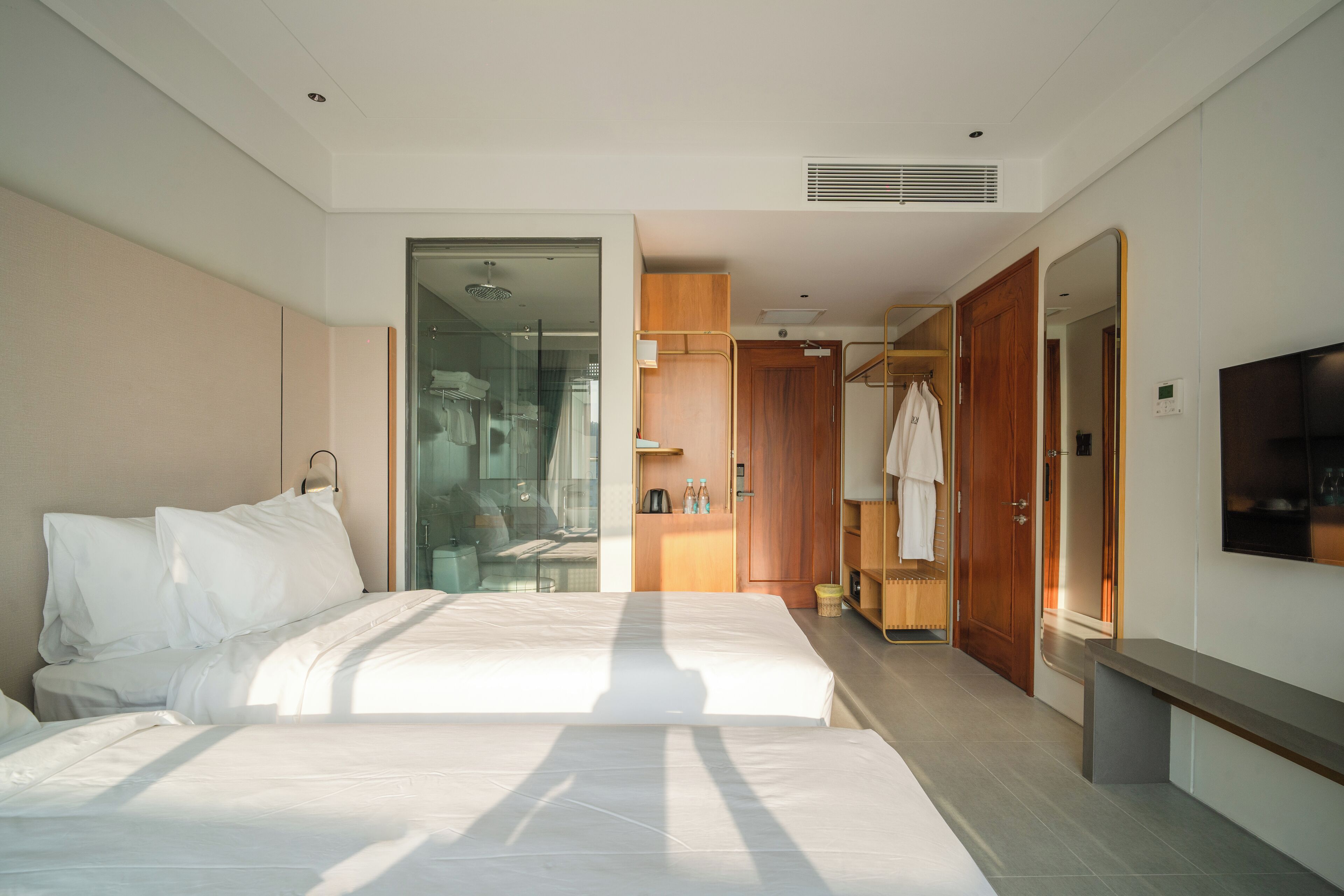 A modern hotel room with a large bed, a walk-in closet, and a TV on the wall.