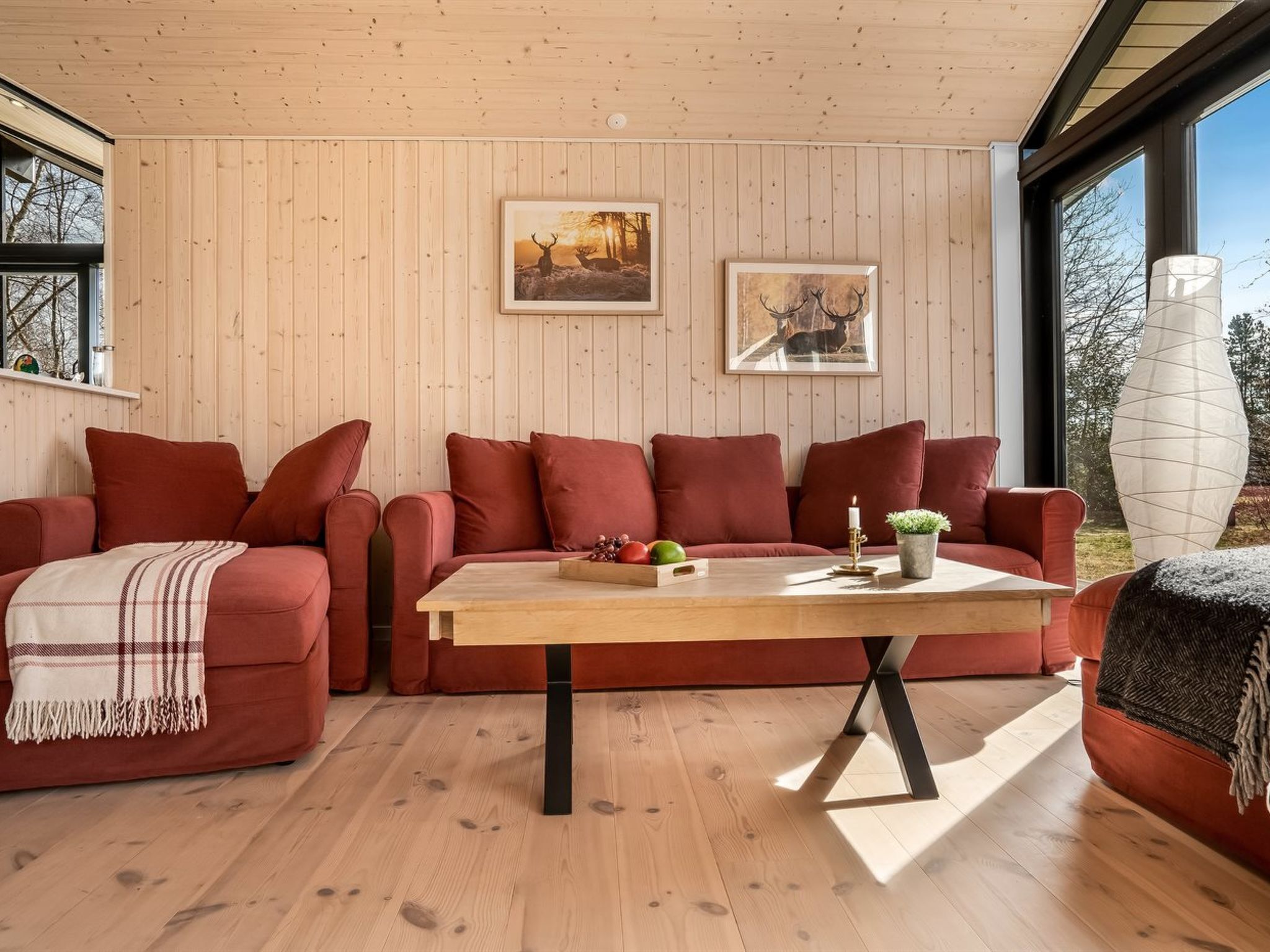 Un accogliente soggiorno con soffitto in legno, un divano rosso, un tavolino da caffè in legno e quadri appesi alle pareti.