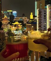 A cityscape at night with illuminated buildings and a traditional structure in the foreground.