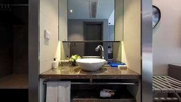 Un baño moderno con un espejo grande, un lavamanos blanco y un perchero para toallas.