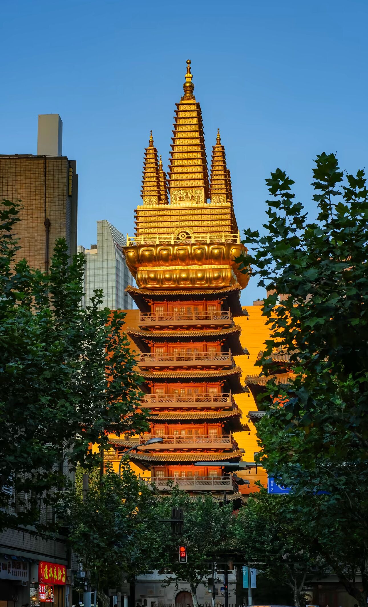 A multi-tiered pagoda with traditional architecture, surrounded by urban buildings and trees.