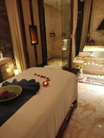 Una camera d'albergo con un letto, una cabina doccia in vetro, una vasca e un pavimento in marmo.