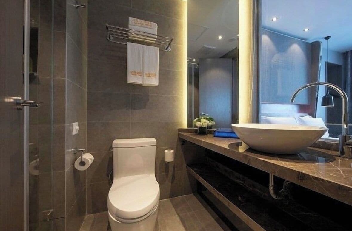 A modern bathroom with a toilet, a large sink, and a mirror.