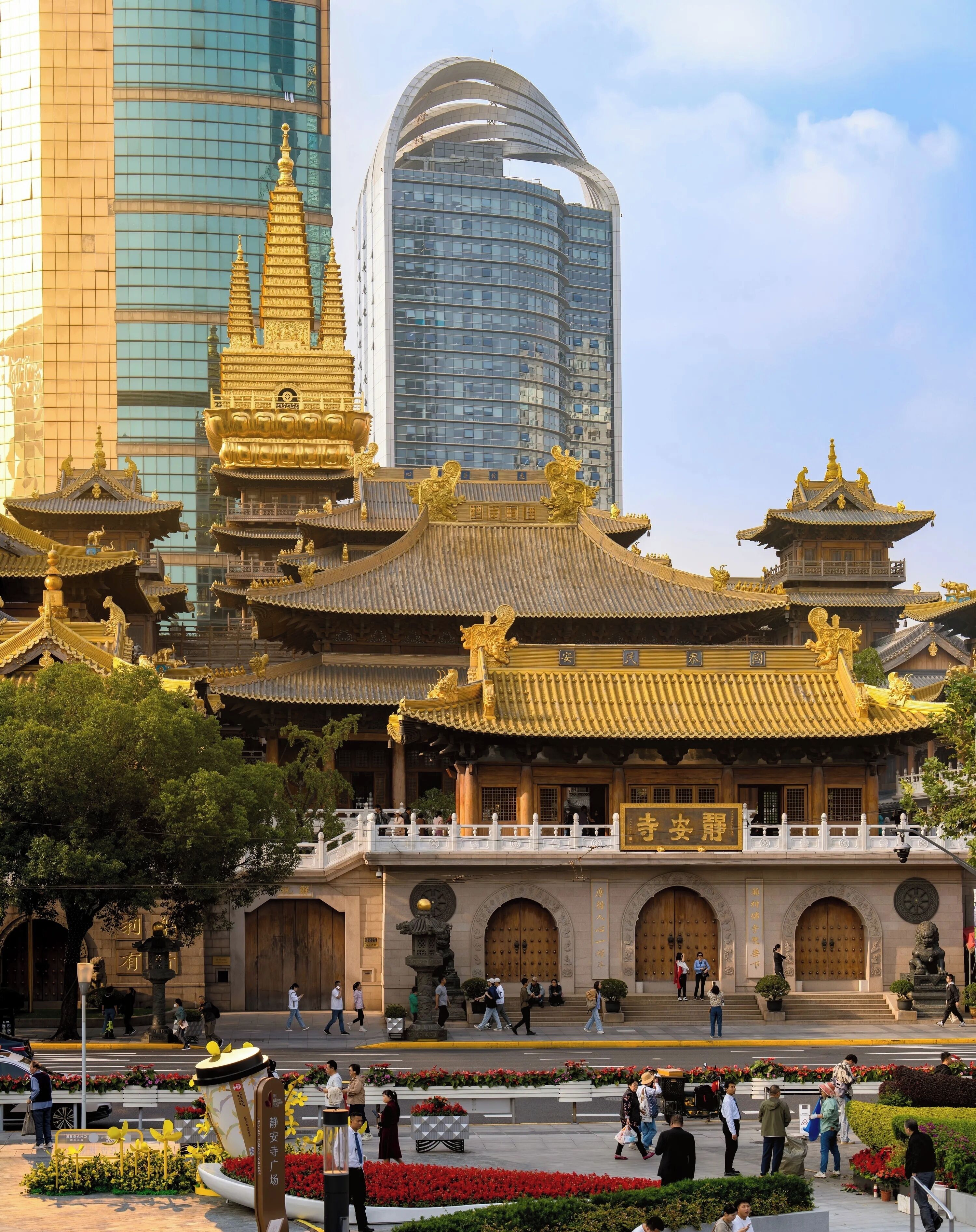 Ein traditionelles chinesisches Gebäude mit aufwendig verzierten goldenen Dächern und einem modernen Wolkenkratzer im Hintergrund.