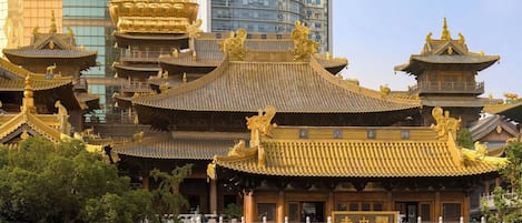 A traditional Chinese building with ornate golden roofs and a modern skyscraper in the background.