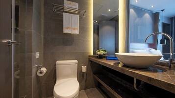 A modern bathroom with a toilet, a large sink, and a shower area.