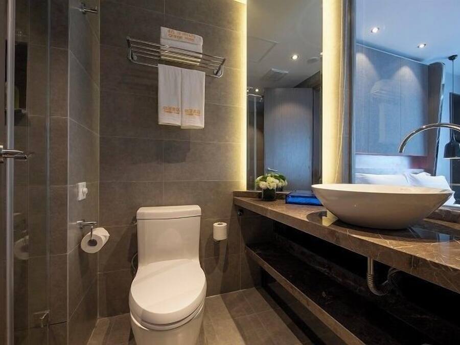 A modern bathroom with a toilet, a large sink, and a shower area.