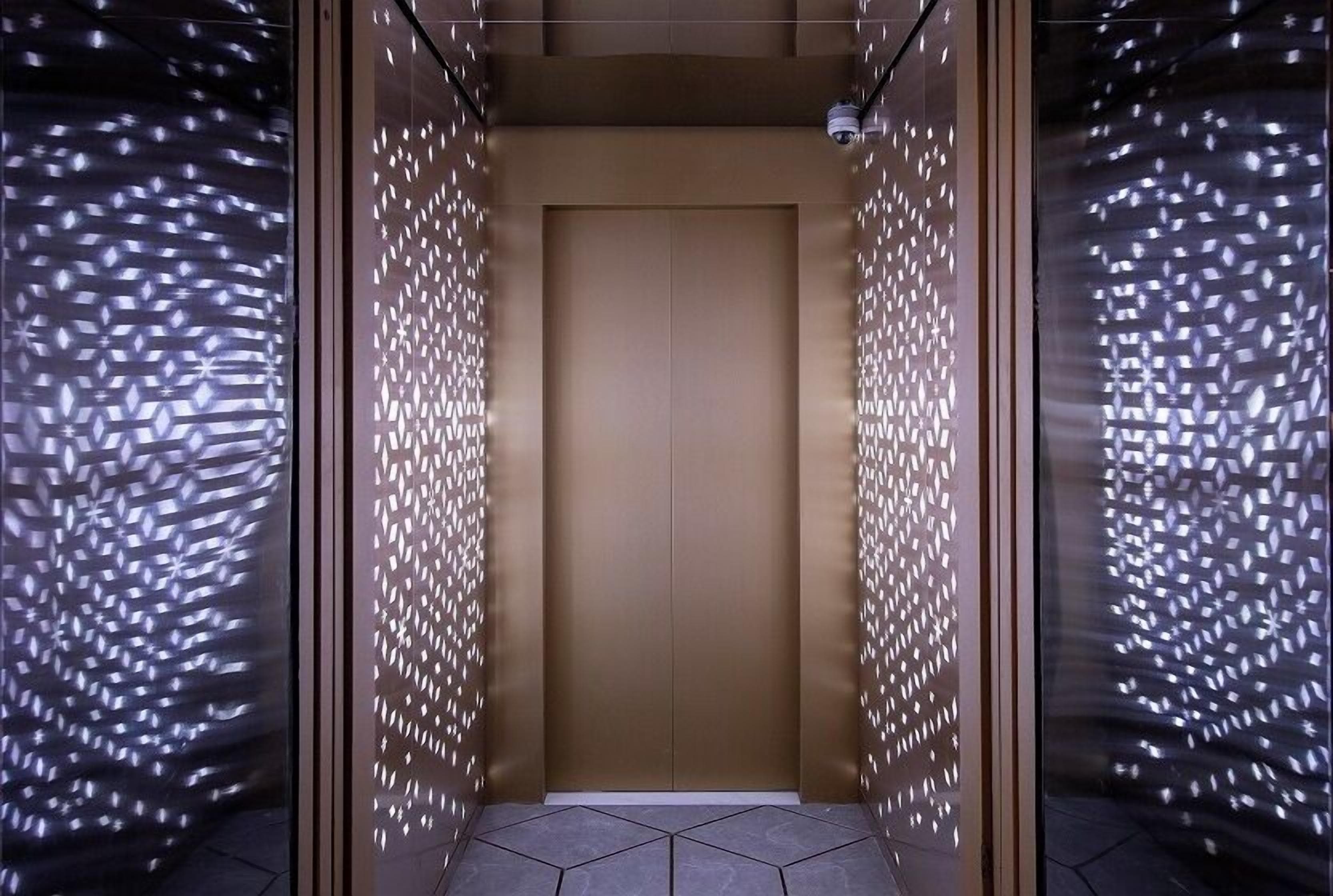 An elevator with a geometric patterned wall and a plain door.