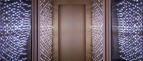 An elevator with a geometric patterned wall and a plain door.