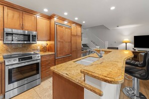 A kitchen with wooden cabinets, a stainless steel Bosch oven, a microwave, and a granite countertop.