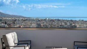 Een balkon met uitzicht op de stad, een stoel en een tafeltje.