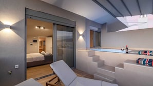 Een moderne hotelkamer met balkon, zwembadje en uitzicht op de stad.