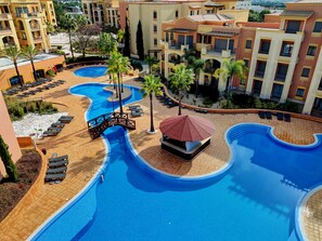 Een resort met diverse zwembaden, ligbedden en palmbomen.