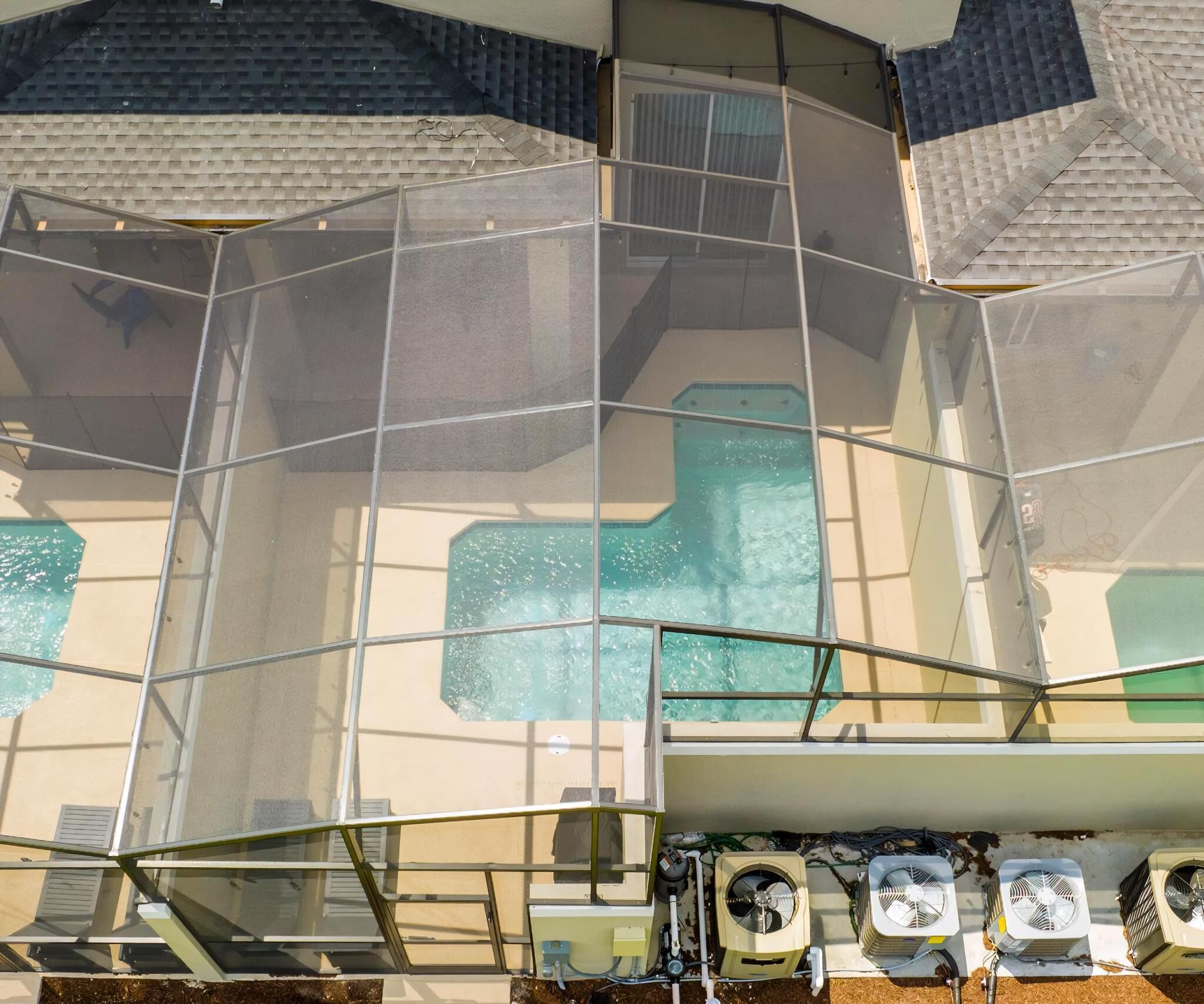 A pool area with clear glass panels and multiple air conditioning units.
