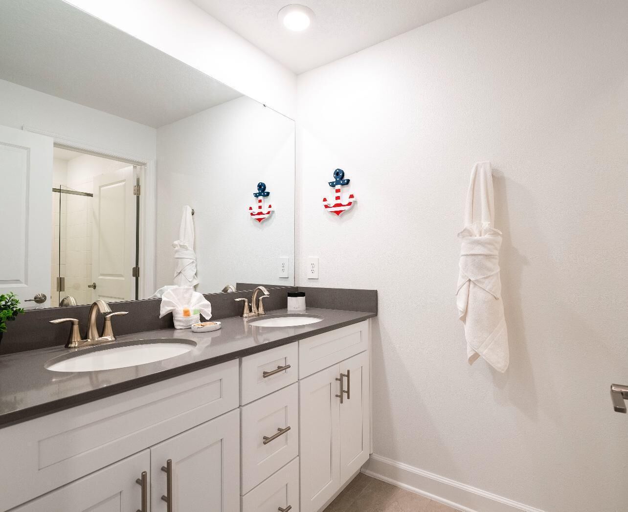 A modern bathroom with two sinks, a large mirror, and a towel rack.