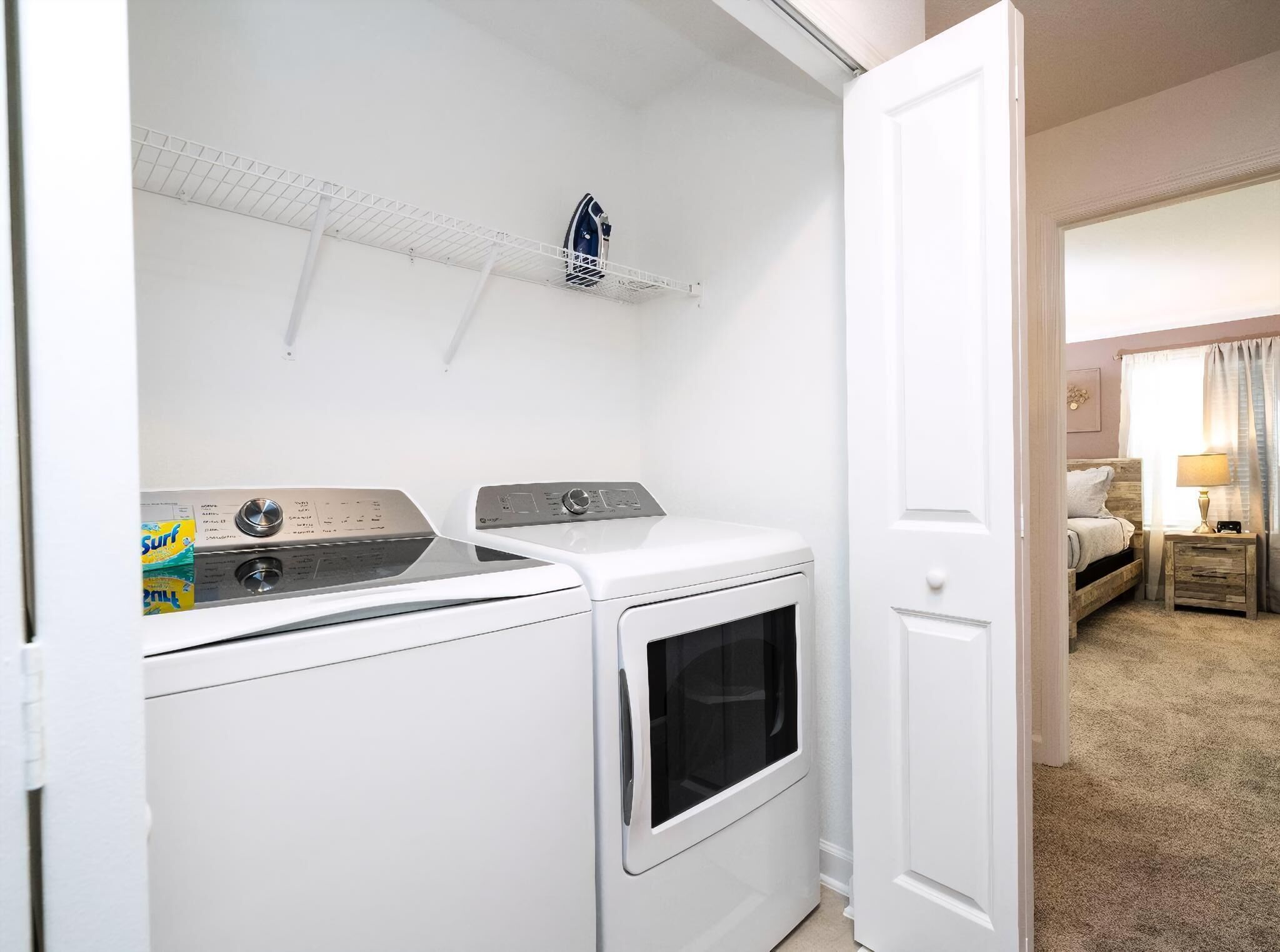 A laundry room with a washing machine, dryer, and ironing board.
