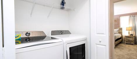 A laundry room with a washing machine, dryer, and ironing board.