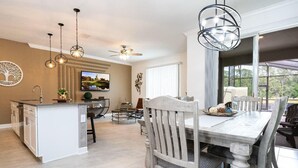 A spacious kitchen with a central island, a dining area with a large table and chairs, and pendant lighting. - Storey Lake Resort, Private Pool, Near Famous Attractions!! (Kissimmee)