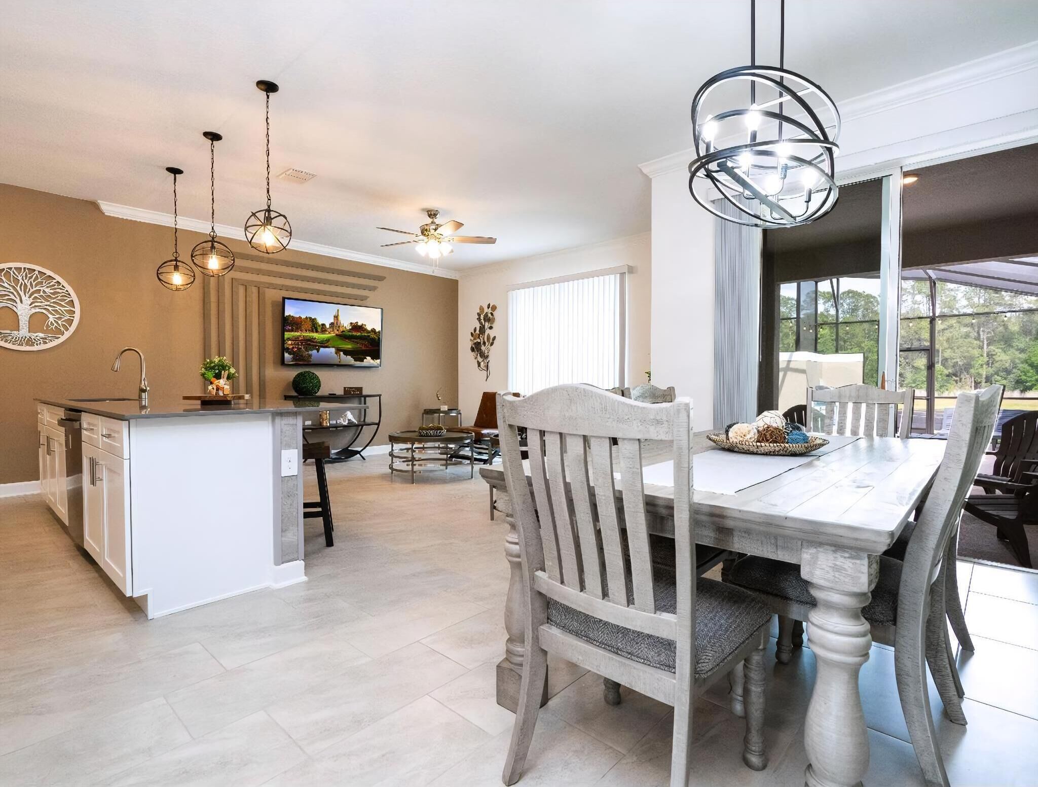 A spacious kitchen with a central island, a dining area with a large table and chairs, and a ceiling fan.
