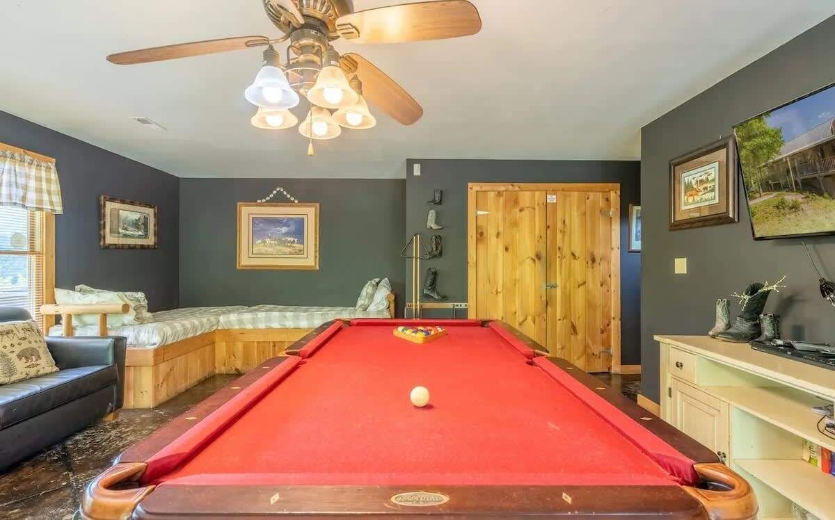 Ein Billardtisch in einem Raum mit Deckenventilator, einer Holzbank und einem gerahmten Bild an der Wand.