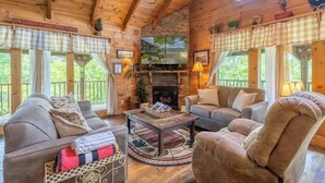 A cozy cabin interior with a fireplace, wooden walls, and a comfortable seating area. - Mountain VIEWS! Private, Hot Tub, & Game Room. (Sevierville)