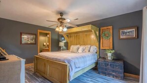 A bedroom with a wooden bed, a ceiling fan, a dresser, and a wall-mounted mirror. - Mountain VIEWS! Private, Hot Tub, & Game Room. (Sevierville)
