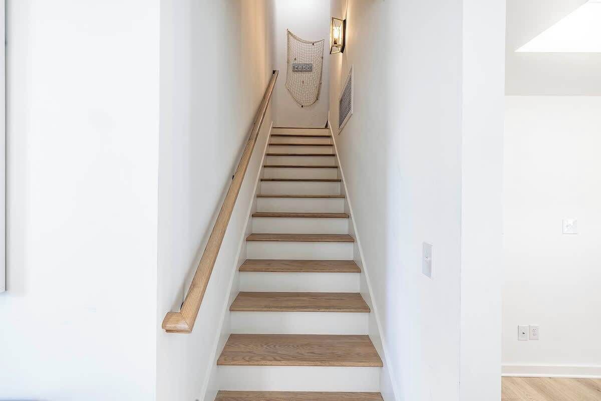 A staircase with wooden steps and a handrail, leading to a landing with a light fixture and a decorative item.