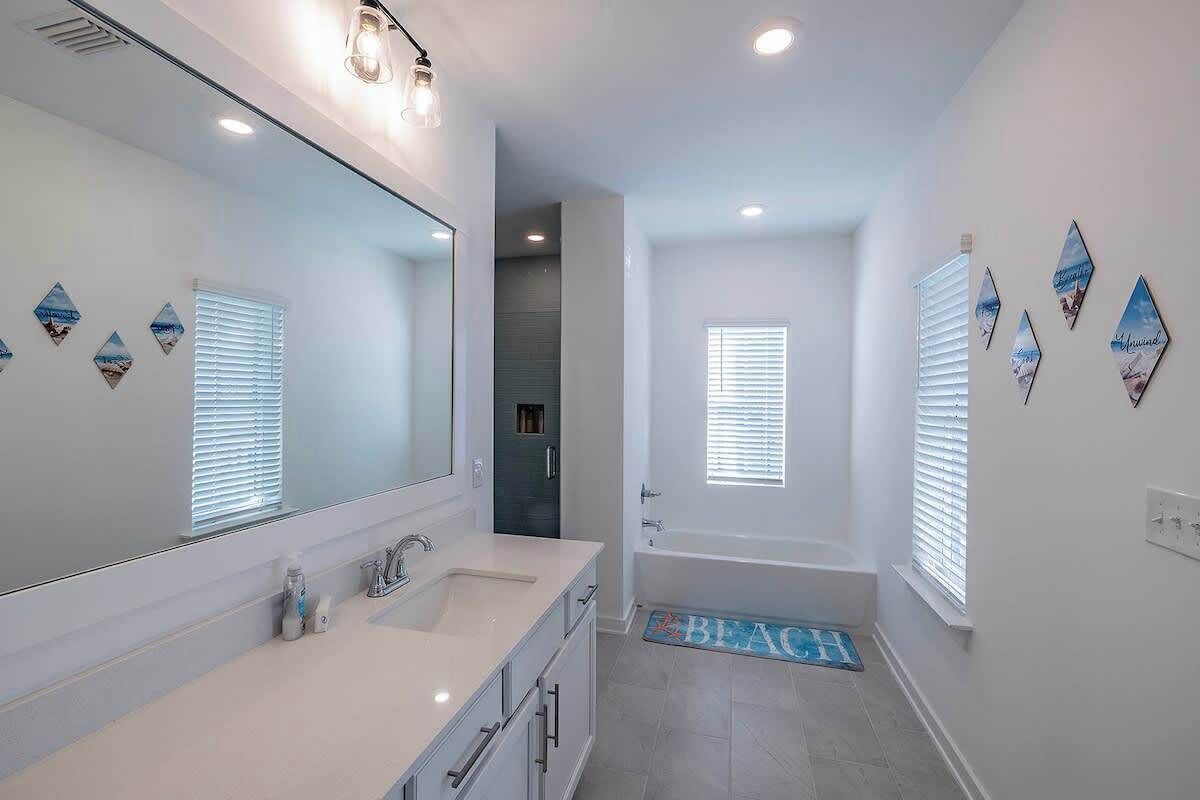 A modern bathroom with a large mirror, a bathtub, and a shower area.