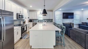 A modern kitchen with white cabinets, stainless steel appliances, and a central island. - Sleeps 16 - GAME ROOM, POOL, Perfect for Families (Orange Beach)
