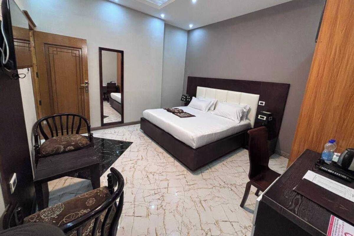 A hotel room with a bed, a desk, a chair, and a TV.