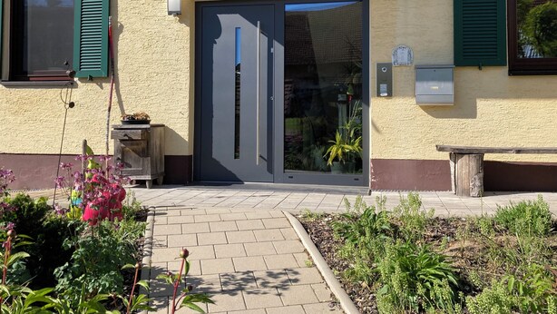 A building with a dark entrance door, green shutters, and a small outdoor seating area. - Holiday apartment in beautiful natural surroundings with the whole family in the immediate vicinity of Ulm. (Neu-Ulm)