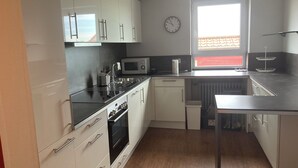 A modern kitchen with white cabinets, stainless steel appliances, and a window with a view. - Holiday apartment in beautiful natural surroundings with the whole family in the immediate vicinity of Ulm. (Neu-Ulm)