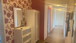 A hallway with a white wardrobe, a mirror, and a floral wallpaper. - Holiday apartment in beautiful natural surroundings with the whole family in the immediate vicinity of Ulm. (Neu-Ulm)
