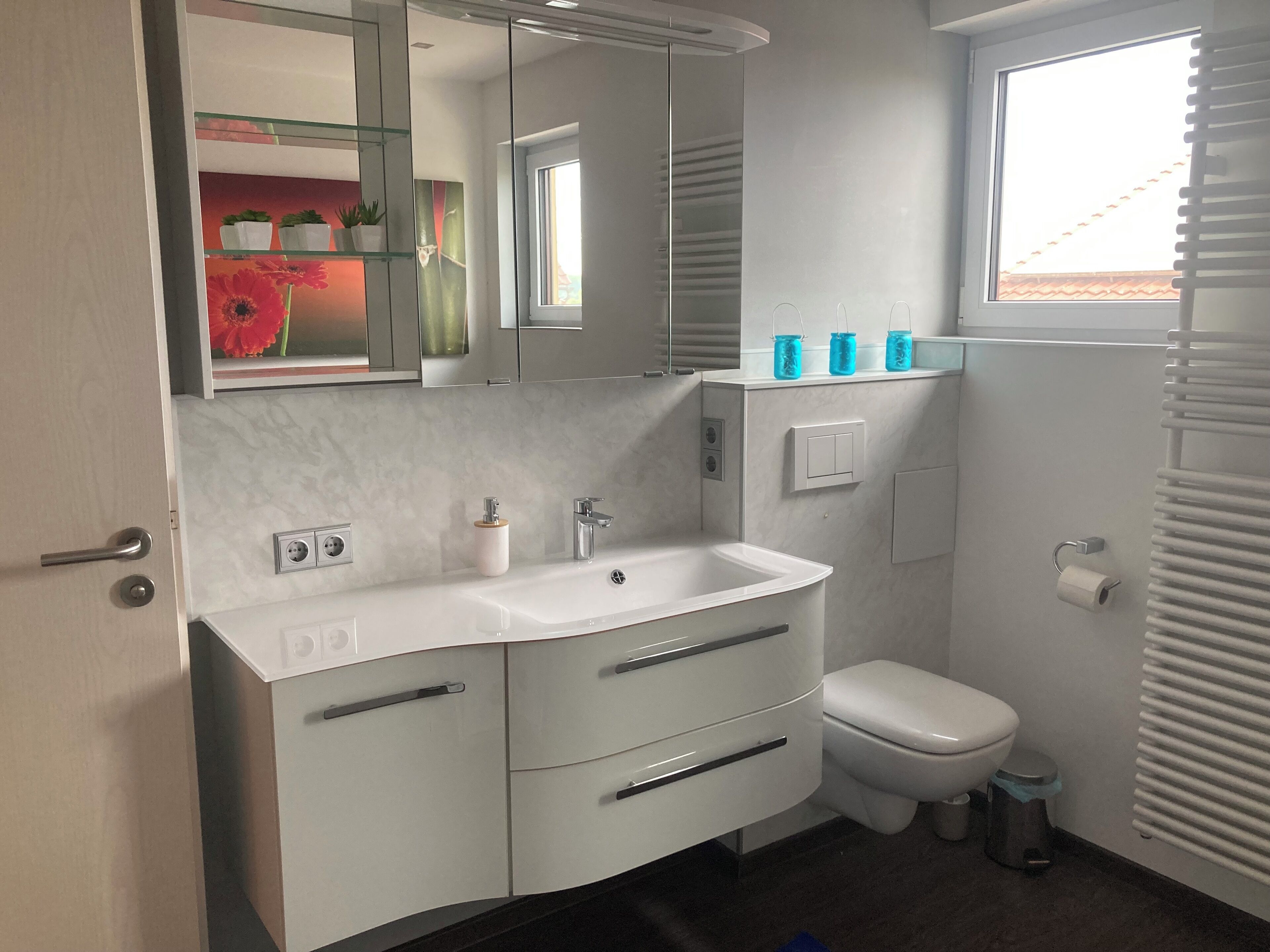 Une salle de bain moderne avec un meuble-lavabo blanc, des toilettes et une fenêtre.