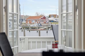 A view from a room with a large window overlooking a marina with boats, a small building, and a dock.
