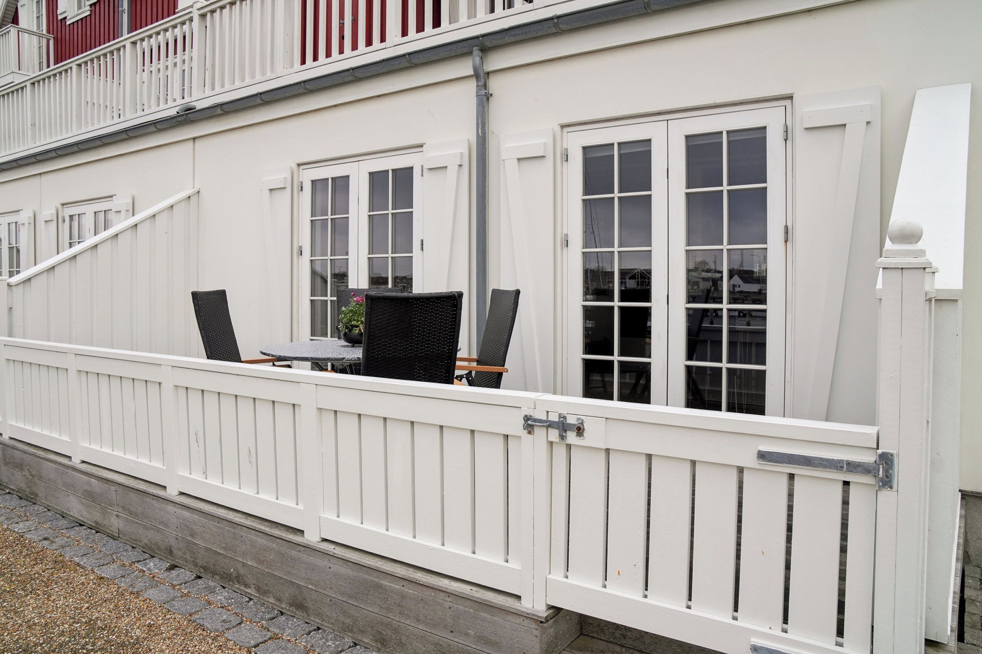 Un bâtiment blanc doté d’un balcon, de balustrades blanches et de deux fenêtres.