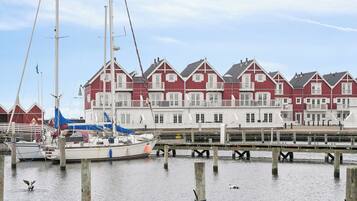 Una hilera de edificios rojos y blancos con un muelle y barcos al frente.