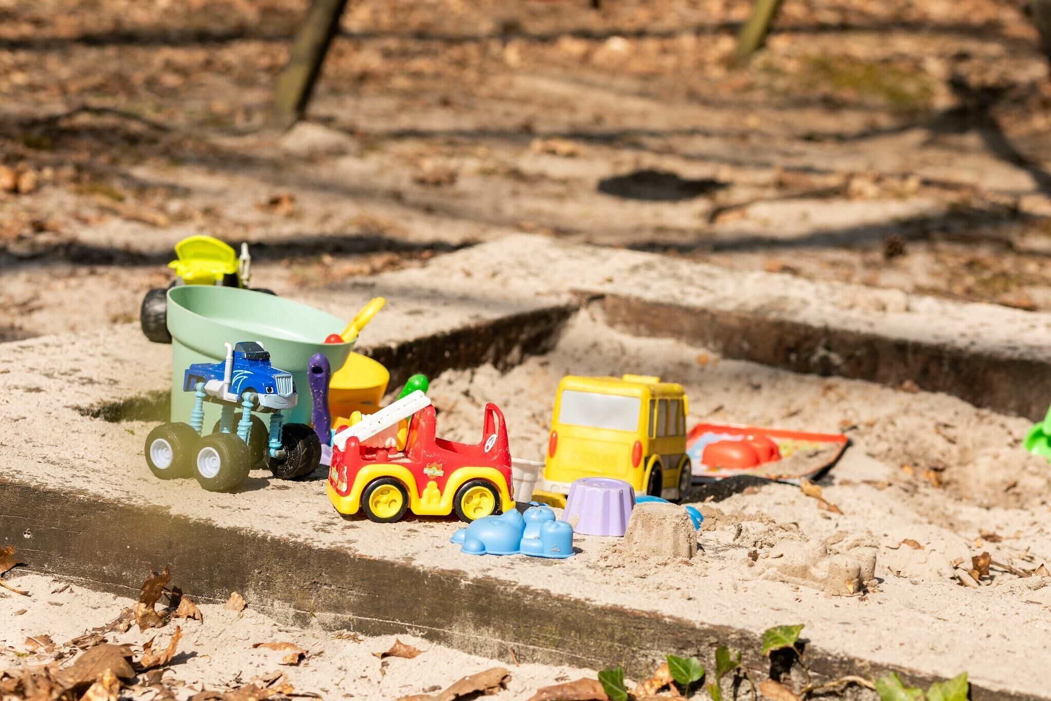 A sandbox with toy vehicles and construction equipment.