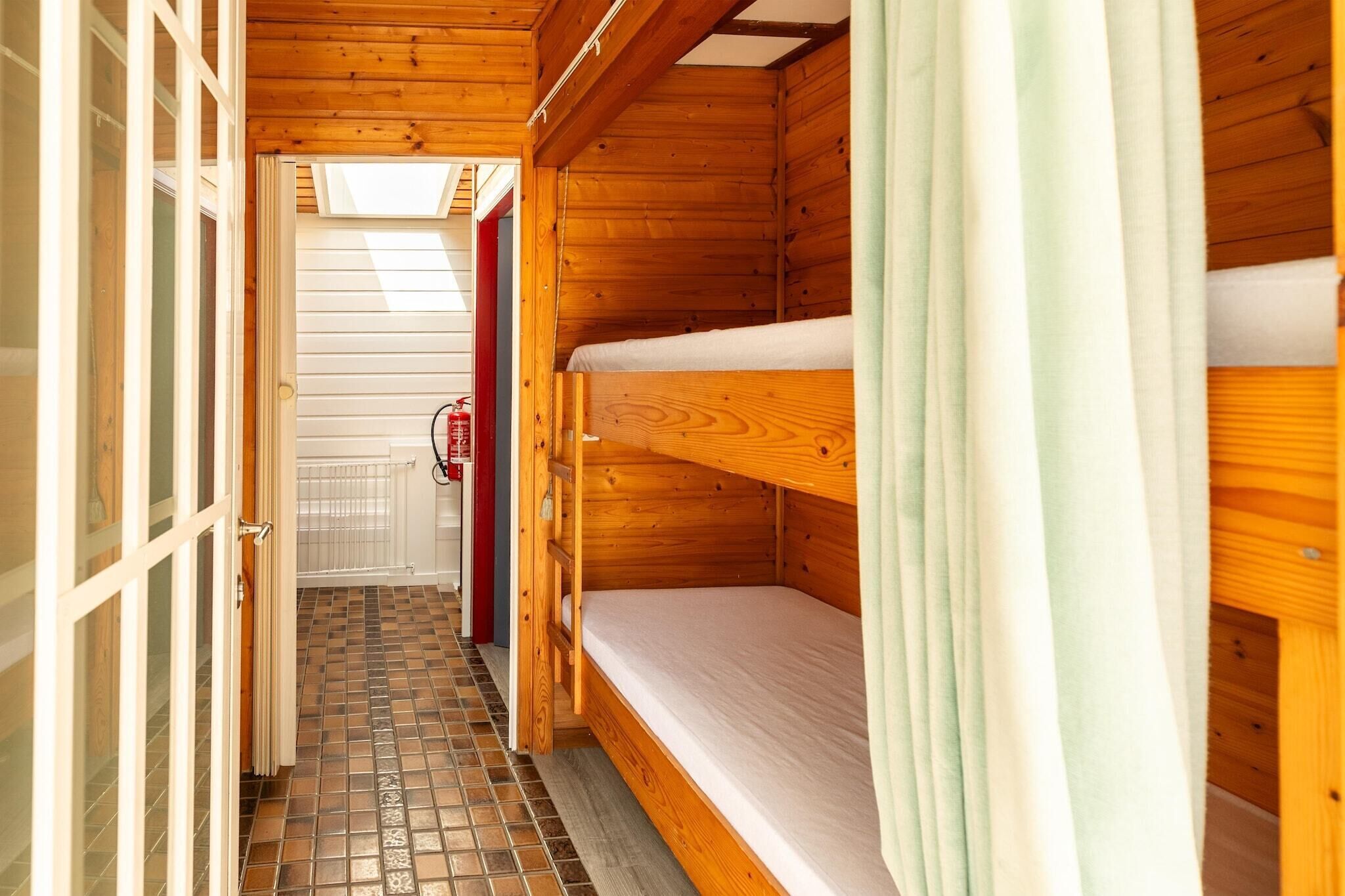 A wooden cabin with bunk beds, a tiled floor, and a fire extinguisher.