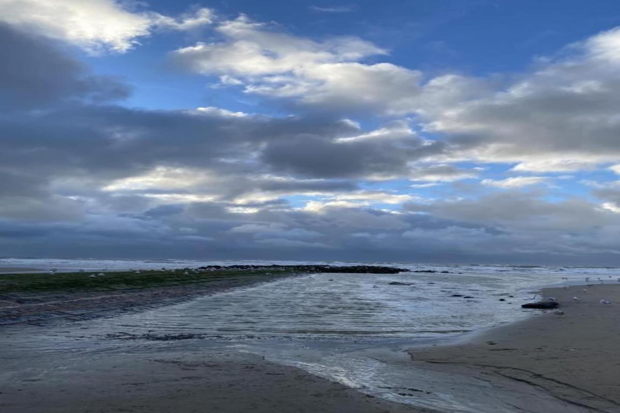 A beach with a rocky breakwater and waves.
